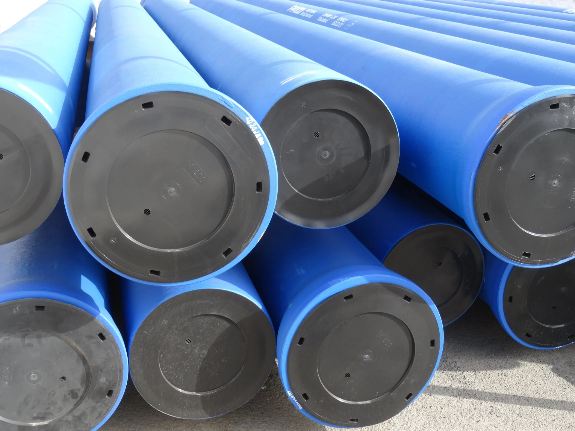 Das Ende eines Stapels blauer PVC-Rohre mit schiefergrauen Verschlusskappen